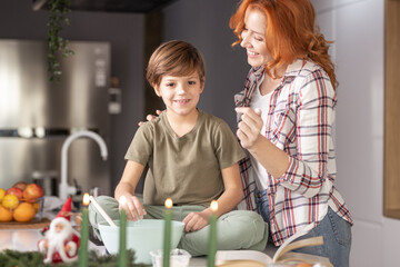 Shot of young women playing with her son, smiling while he is sitting on kitchen table.
Having fun while making cookies, leisure time
Family time stock photo