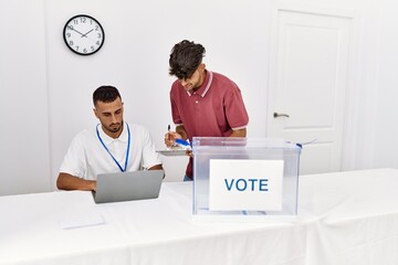 Two hispanic politic party workers smiling happy working at electoral college.