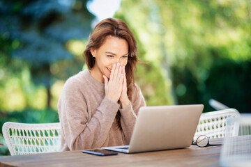 Happy middle aged woman using a laptop while siting at balcony at home