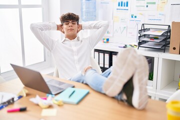 Young hispanic teenager business worker relaxed with hands on head at office