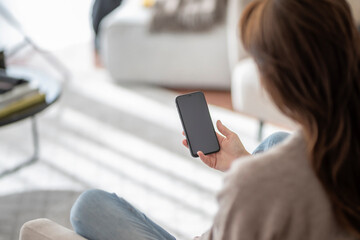 ong haired woman holding a blank screen cellphone in her hand