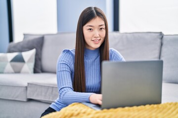 Chinese woman using laptop sitting on floor at home