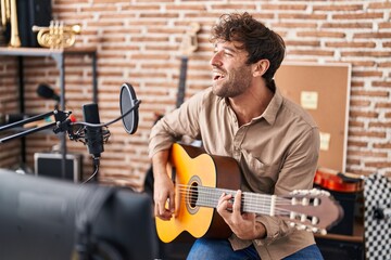 Young man musician singing song playing classical guitar at music studio - Powered by Adobe