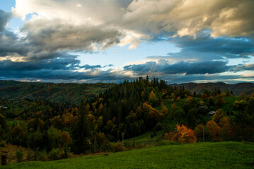 Sunset in the mountain village of the Ukrainian Carpathians with thick clouds and a beautiful view of the forest hill and rural houses