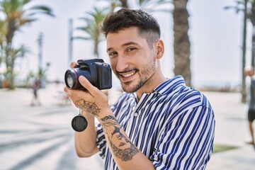 Young handsome man using dslr photography camera by the sea