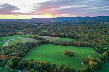 Obraz premium Brilliant Sunset in early fall over Wantage Township Sussex County NJ with large fields and foliage and Kittatiny Mountains in background aerial