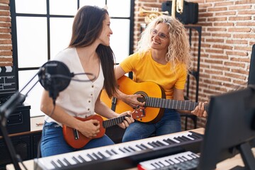 Two women musicians playing classical guitar and ukulele at music studio
