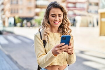 Young woman tourist smiling confident using smartphone at street