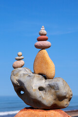 Rock zen pyramid of stones of different shapes on a background of blue sky and sea.