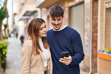 Mand and woman couple using smartphone standing together at street