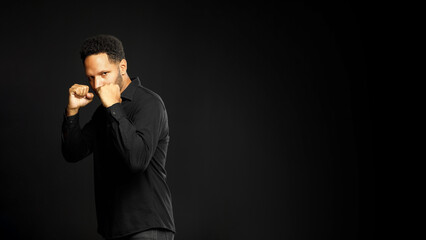 Man American In Black Shirt Boxing Stance On Black Background Copy Space