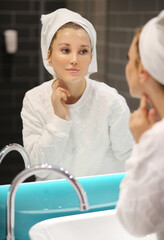 Woman looking in the mirror Applying the cream..Magic anti-aging cream.