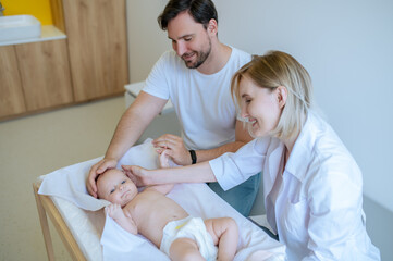 Obraz na płótnie Canvas Experienced doctor performing a neonatal exam in the dad presence