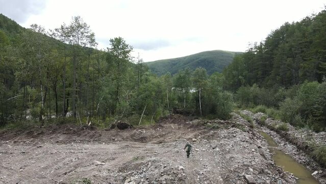 View from above. Zeya Nature Reserve in summer. The bed of a large river, polluted by gold miners, flows into a protected lake. An ecologist walks along an open stream.
