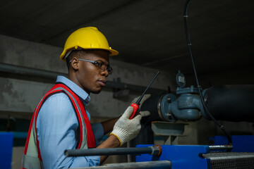 Worker Inspecting Water Valve For Leaks In Basement of a huge factory. - obrazy, fototapety, plakaty