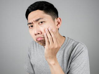Close up asian man grey shirt feels worried about acne of his face isolated