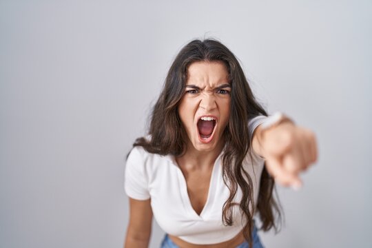 Young teenager girl standing over white background pointing displeased and frustrated to the camera, angry and furious with you