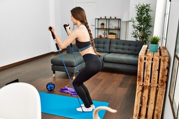 Young hispanic woman smiling confident having online traininig using elastic band at home