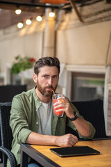 Young bearded man sitting in the cafe and having a break in work