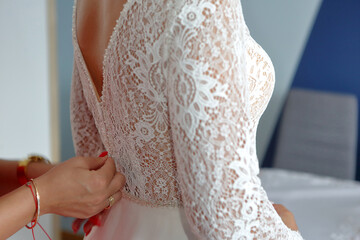 Beautiful bride dress is fastened by a witness. Back, hands, close-up