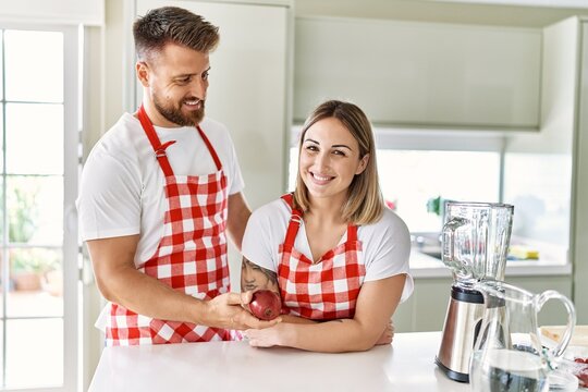 Young couple smiling confident holding red apple at kitchen