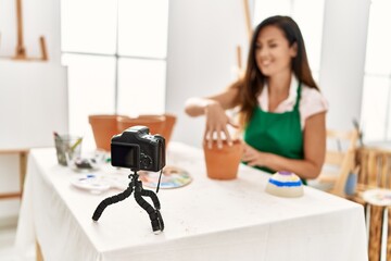 Middle age hispanic woman smiling confident having online art class at art studio