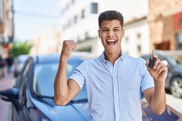 Young hispanic man holding car key screaming proud, celebrating victory and success very excited...