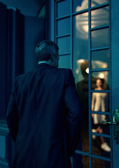 Man in suit stands outside in front of an closed front door with a woman inside at night. 3D render.