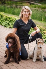 Portrait of glad woman with two dogs in park in summertime on vacations.