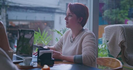 One happy red hair adult girl talking with friend seated at cafe restaurant. A candid redhead young woman speaking with colleague off camera