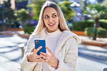 Young woman smiling confident using smartphone at street