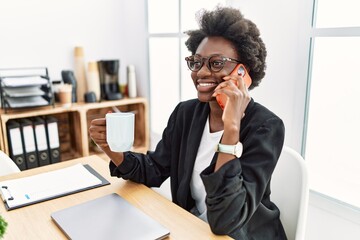 Young african american woman speaking on the phone drinking coffee at office