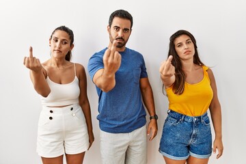 Group of young hispanic people standing over isolated background showing middle finger, impolite...