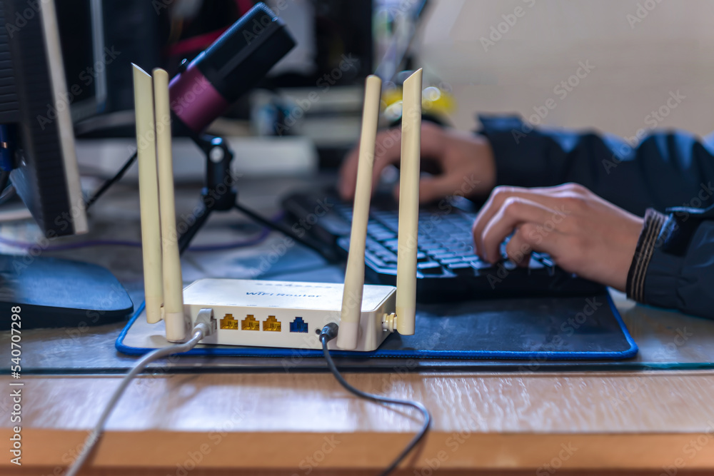 Poster a person is sitting at a computer in the foreground of a wifi router