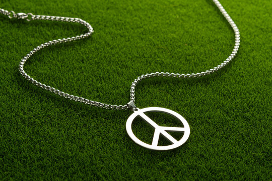 Metal medallion, with a pendant in the form of a symbol of peace on a green grass.