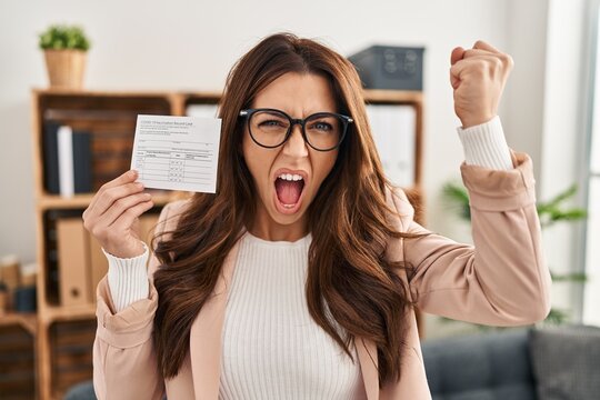 Young Brunette Woman Holding Covid Record Card Annoyed And Frustrated Shouting With Anger, Yelling Crazy With Anger And Hand Raised