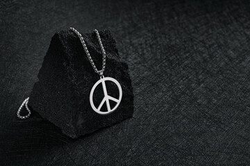 Fototapeta na wymiar Metal medallion, with a pendant in the form of a mark of peace on a black stone.