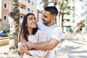 Young latin couple smiling happy and hugging at the city.