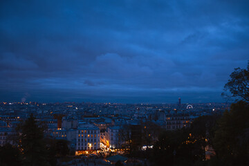 Paris night view from Montmartre hill. Beautiful evening blue hour cityscape with street lights background. France winter travel tourism.