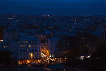 Paris night view from Montmartre hill. Beautiful evening blue hour cityscape with street lights background. People shopping crowd. France winter travel tourism.