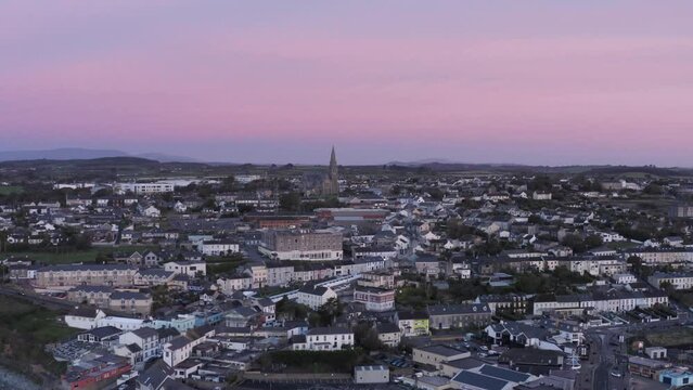 Pink sky dawn aerial rises over coastal town of Tramore, Ireland