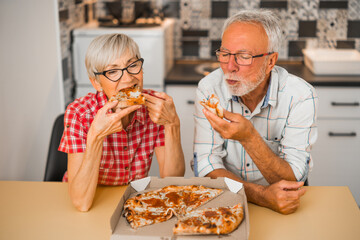 Senior couple eating pizza at home.