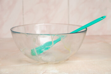 Dirty transparent glass bowl with silicone shovel. Dirty glass bowl after cooking. Dirty silicone shovel after home cooking.