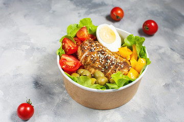 Buddha bowl salad with grilled chicken breast slices, cherry tomatoes, eggs, avocado, lettuce and seeds on concrete background.
