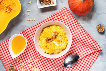 Rice milk pumpkin porridge with walnuts, butter and honey on a concrete table. Healthy food.