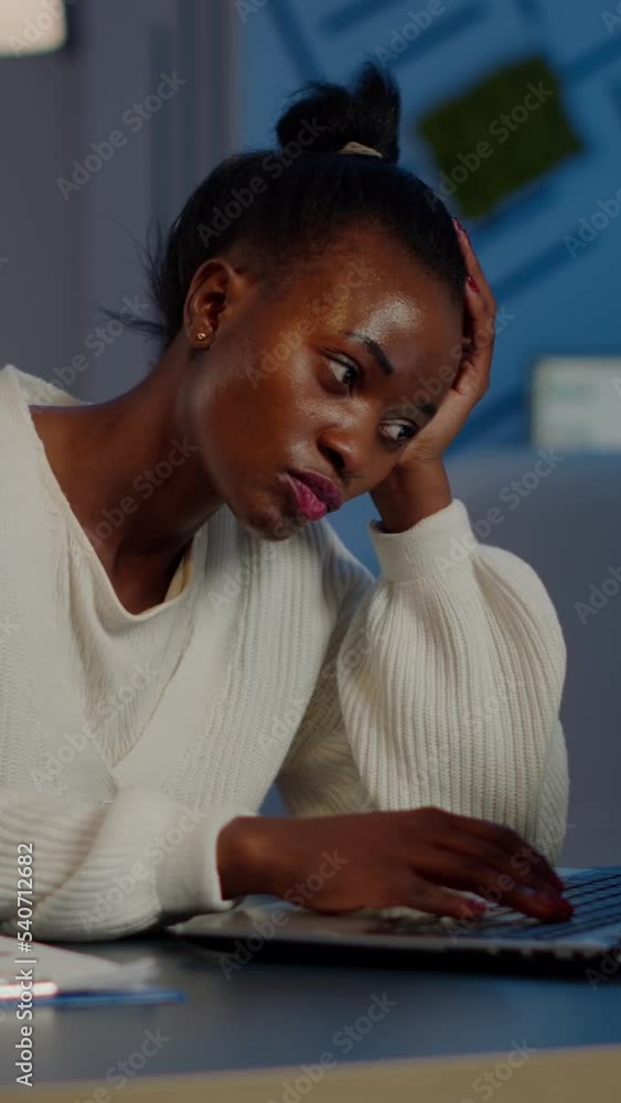 Poster exhausted african freelancer resting head on hand in front of laptop working overtime in start up co