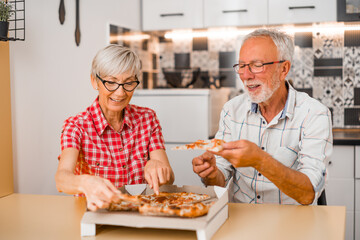 Senior couple eating pizza at home.