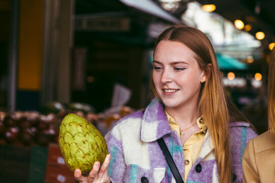 Happy woman looking at custard apple in farmer's market