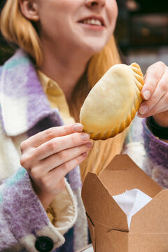 Happy young woman holding empanada