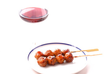 炭火でじっくり焼いた焼き鳥のつくね串（タレ）と赤ワインのグラス